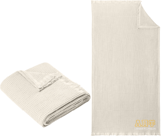 Folded beige blanket next to a larger unfolded beige blanket on a white background