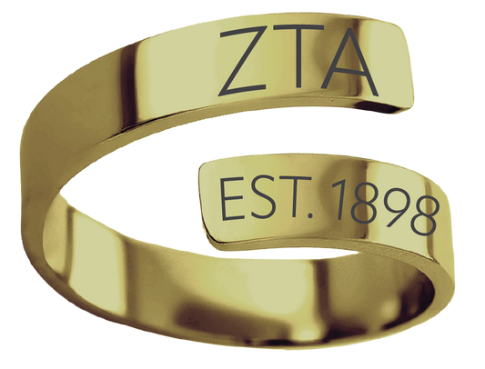 A polished gold-colored open band ring engraved with the Greek letters 'ΑΣΑ' on the top segment and 'EST. 1907' on the lower segment, isolated on a white background.