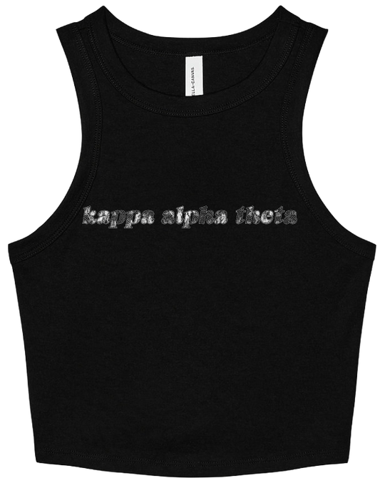 A black sleeveless crop top tank top featuring the text 'kappa alpha theta' printed across the chest in a textured silver glitter font. The shirt is displayed flat against a solid white background.