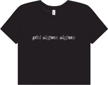 A black short-sleeve crewneck t-shirt featuring the text 'phi sigma sigma' printed across the chest in a textured silver glitter pattern, displayed on a clean white background.
