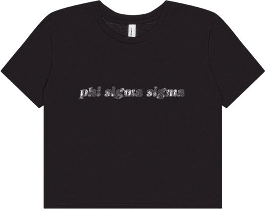 A black short-sleeve crewneck t-shirt featuring the text 'phi sigma sigma' printed across the chest in a textured silver glitter pattern, displayed on a clean white background.